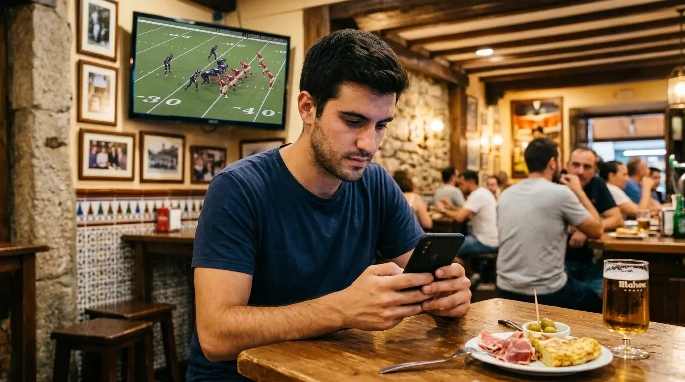 Persona mirando un partido de fútbol americano en el móvil desde un bar en España